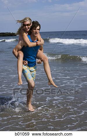 Young man carrying a young woman on his back View Large Photo Image Stock Photo - Young man carrying a young woman on his back. Fotosearch