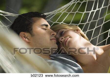 Stock Image - Close-up of a young couple sleeping in a hammock. Fotosearch