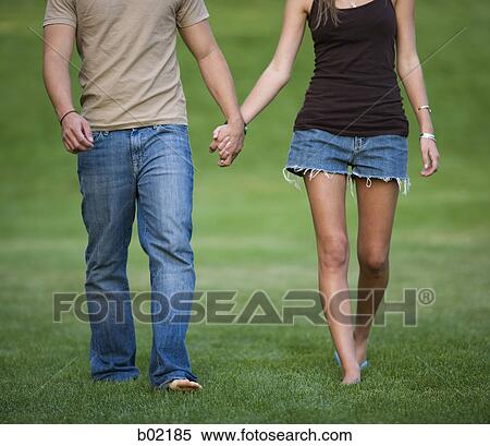 Close-up of a young man and woman holding hands and walking in a park View Large Photo Image Stock Photography - Close-up of a young man and woman holding hands and walking in a park. Fotosearch