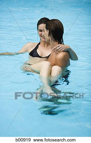 High angle view of a young man in a swimming pool, carrying a young woman View Large Photo Image Stock Photo - High angle view of a young man in a swimming pool, carrying a young woman. Fotosearch