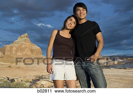 Stock Image - Low angle view of a young couple standing. Fotosearch