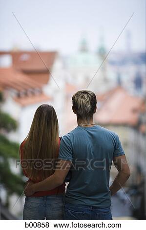 Rear view of a young man standing with a young woman View Large Photo Image Stock Photo - Rear view of a young man standing with a young woman. Fotosearch