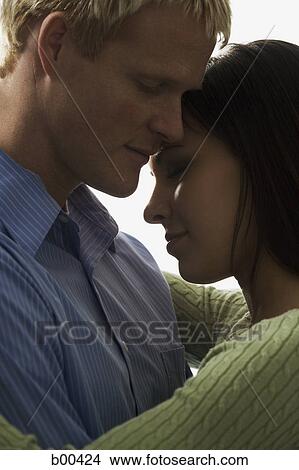 Side profile of a young couple embracing each other View Large Photo Image Picture - Side profile of a young couple embracing each other. Fotosearch