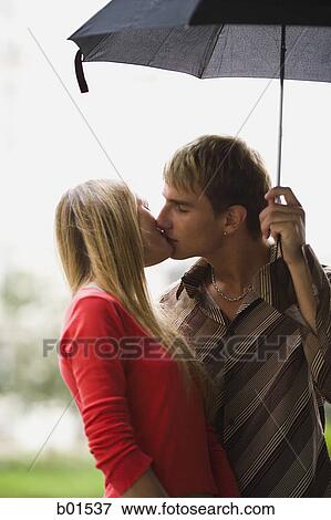 Stock Photo - Teenage couple kissing under an umbrella. Fotosearch