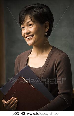 Close-up of a teacher holding files and smiling View Large Photo Image Stock Image - Close-up of a teacher holding files and smiling. Fotosearch