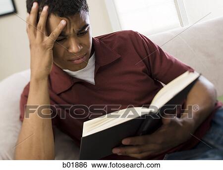 Close-up of a young man reading a book View Large Photo Image Stock Photograph - Close-up of a young man reading a book. Fotosearch