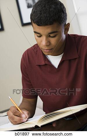 Close-up of a young man writing on a notebook View Large Photo Image Stock Photo - Close-up of a young man writing on a notebook. Fotosearch