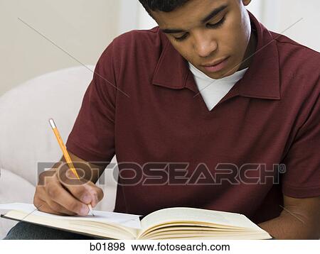 Stock Photo - Close-up of a young man writing on a notebook. Fotosearch