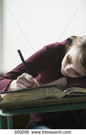 Girl holding a pen and writing at a desk View Large Photo Image Stock Photograph - Girl holding a pen and writing at a desk. Fotosearch