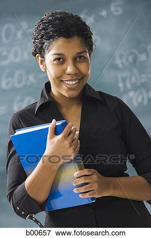 Stock Photo - Portrait of a young woman holding a book and smiling. Fotosearch