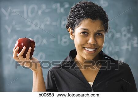 Portrait of a young woman holding an apple View Large Photo Image Stock Photo - Portrait of a young woman holding an apple. Fotosearch
