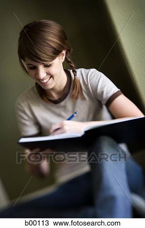 Stock Image - Young woman writing on a notebook. Fotosearch