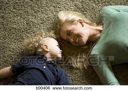 High angle view of a mother and her daughter lying on carpet View Large Photo Image Stock Photograph - High angle view of a mother and her daughter lying on carpet. Fotosearch