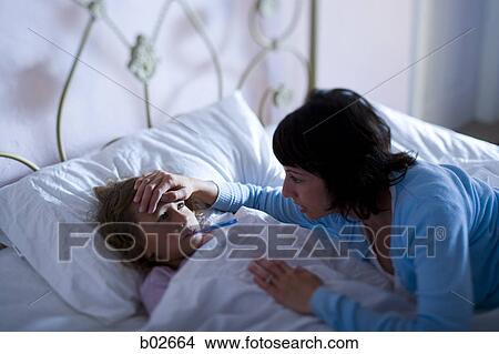 High angle view of a mother checking her daughter's temperature View Large Photo Image Picture - High angle view of a mother checking her daughter's temperature. Fotosearch