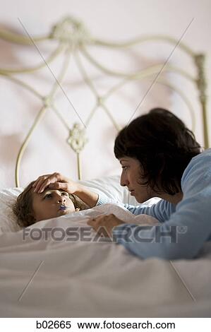 High angle view of a mother checking her daughter's temperature View Large Photo Image Stock Photography - High angle view of a mother checking her daughter's temperature. Fotosearch