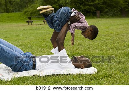 Stock Image - Portrait of a father lifting his son. Fotosearch