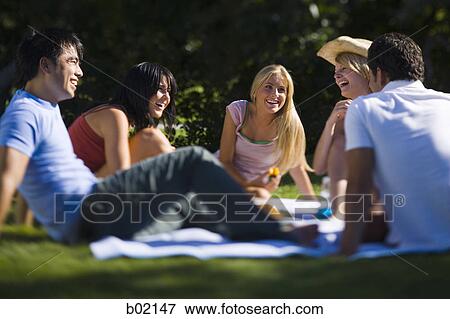 Four young people sitting in a park View Large Photo Image Stock Photo - Four young people sitting in a park. Fotosearch