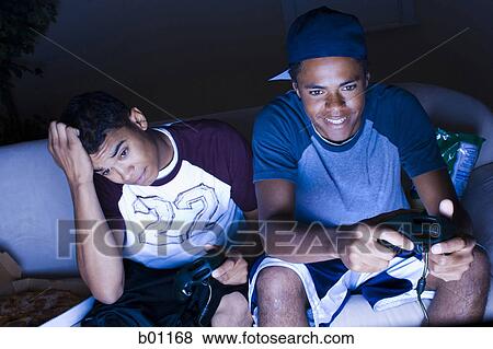 Stock Photo - High angle view of a young men playing a video game. Fotosearch