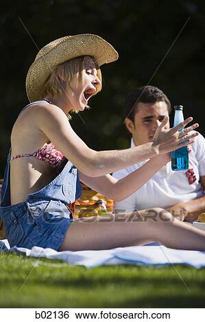 Low angle view of a young woman holding a beer bottle View Large Photo Image Stock Photograph - Low angle view of a young woman holding a beer bottle. Fotosearch