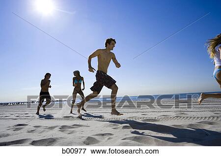 Low angle view of four young people running on the beach View Large Photo Image Stock Photo - Low angle view of four young people running on the beach. Fotosearch