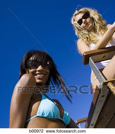Low angle view of two young women on the beach View Large Photo Image Stock Image - Low angle view of two young women on the beach. Fotosearch