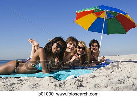 Portrait of four young people lying on the beach View Large Photo Image Stock Image - Portrait of four young people lying on the beach. Fotosearch