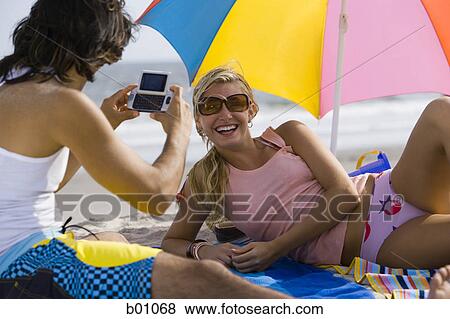 Rear view of a young man taking a young woman's photograph View Large Photo Image Stock Photo - Rear view of a young man taking a young woman's photograph. Fotosearch