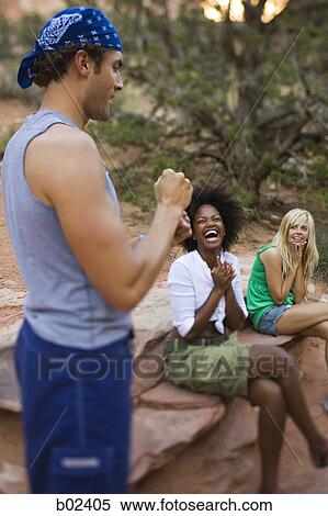 Two young women sitting and smiling at a young man View Large Photo Image Stock Photography - Two young women sitting and smiling at a young man. Fotosearch