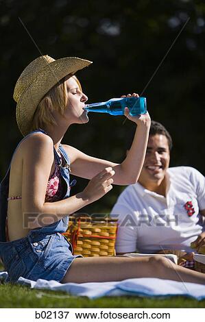 Young woman drinking beer in a park View Large Photo Image Stock Photo - Young woman drinking beer in a park. Fotosearch