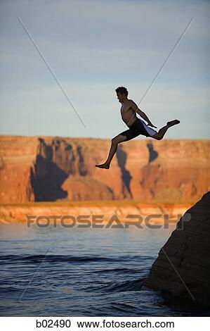 Low angle view of a young man jumping into a lake View Large Photo Image Stock Image - Low angle view of a young man jumping into a lake. Fotosearch