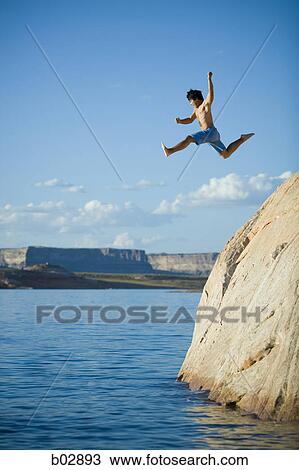 Low angle view of a young man jumping into a lake View Large Photo Image Stock Image - Low angle view of a young man jumping into a lake. Fotosearch
