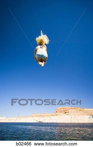 Low angle view of a young woman jumping in water View Large Photo Image Stock Photograph - Low angle view of a young woman jumping in water. Fotosearch