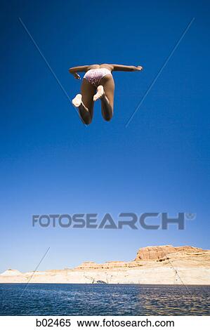 Low angle view of a young woman jumping in water View Large Photo Image Stock Photography - Low angle view of a young woman jumping in water. Fotosearch