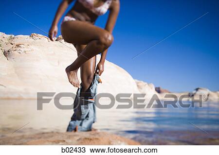 Stock Image - Low angle view of a young woman undressing. Fotosearch