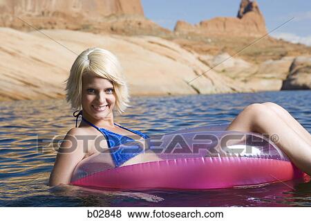 Stock Photo - Portrait of a young woman sitting in an inflatable raft in a lake. Fotosearch