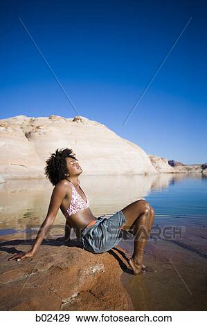 Profile of a young woman sitting on a rock with her eyes closed View Large Photo Image Stock Photo - Profile of a young woman sitting on a rock with her eyes closed. Fotosearch