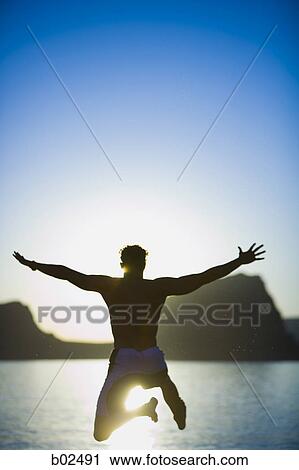 Rear view of a young man diving in a lake View Large Photo Image Stock Image - Rear view of a young man diving in a lake. Fotosearch
