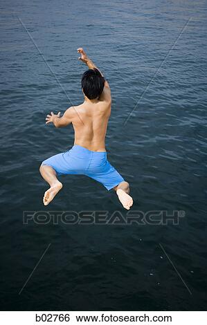 Rear view of a young man jumping in a lake View Large Photo Image Stock Photograph - Rear view of a young man jumping in a lake. Fotosearch