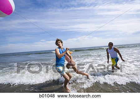Three young people playing with a beach ball in the sea View Large Photo Image Stock Photo - Three young people playing with a beach ball in the sea. Fotosearch