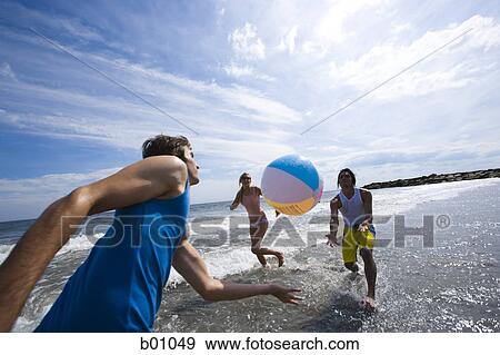 Three young people playing with a beach ball in the sea View Large Photo Image Stock Photo - Three young people playing with a beach ball in the sea. Fotosearch