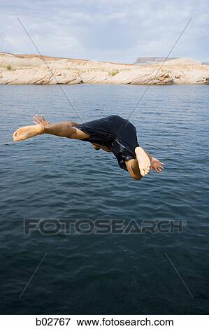 Young man jumping into a lake View Large Photo Image Stock Photo - Young man jumping into a lake. Fotosearch