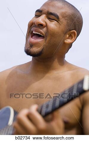 Close-up of a young man playing a guitar View Large Photo Image Picture - Close-up of a young man playing a guitar. Fotosearch