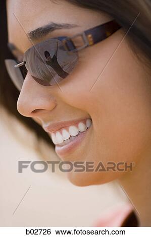 Close-up of a young woman wearing sunglasses View Large Photo Image Stock Photograph - Close-up of a young woman wearing sunglasses. Fotosearch