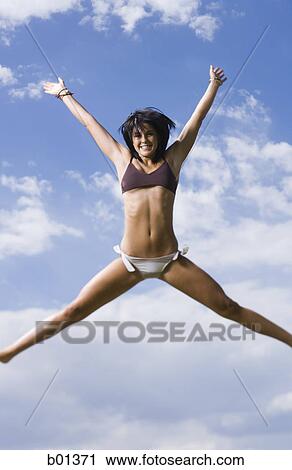 Low angle view of a young woman jumping View Large Photo Image Stock Image - Low angle view of a young woman jumping. Fotosearch