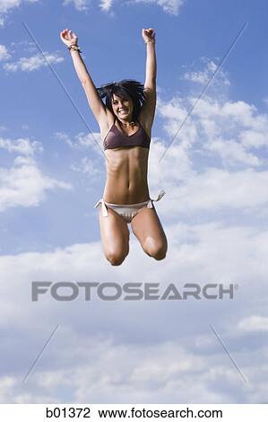 Low angle view of a young woman jumping View Large Photo Image Stock Image - Low angle view of a young woman jumping. Fotosearch