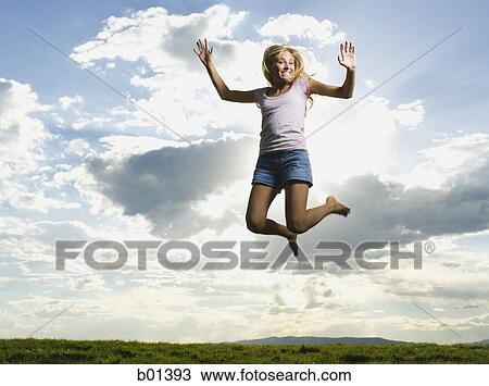 Low angle view of a young woman jumping View Large Photo Image Stock Image - Low angle view of a young woman jumping. Fotosearch