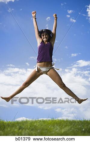 Low angle view of a young woman jumping View Large Photo Image Stock Photo - Low angle view of a young woman jumping. Fotosearch
