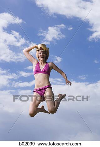 Low angle view of a young woman jumping View Large Photo Image Stock Photo - Low angle view of a young woman jumping. Fotosearch