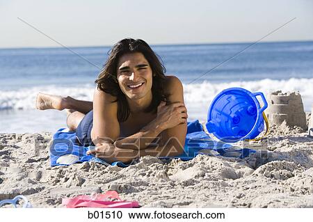 Stock Image - Portrait of a young man lying on the beach. Fotosearch