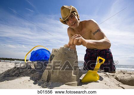 Portrait of a young man making a sand castle View Large Photo Image Stock Photograph - Portrait of a young man making a sand castle. Fotosearch